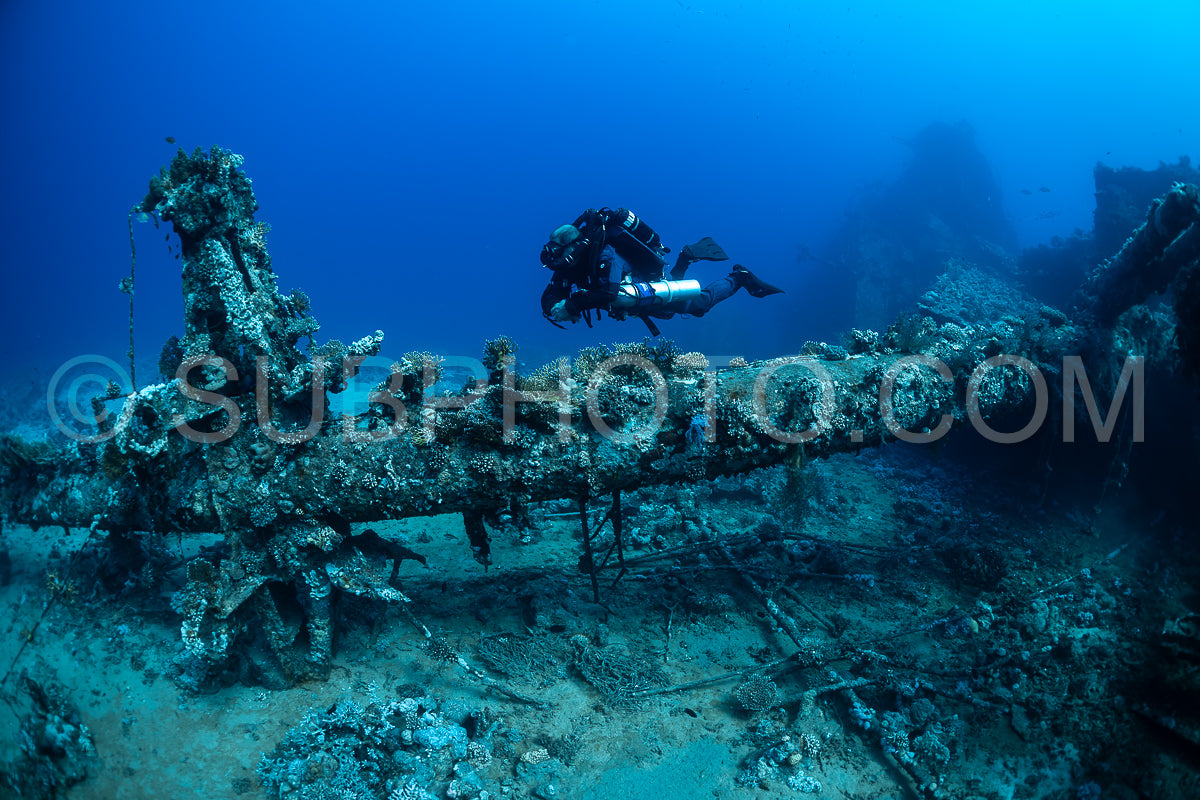 A diver using a rebreather swims past the overgrown remains of a sunken ship in the Red Sea.