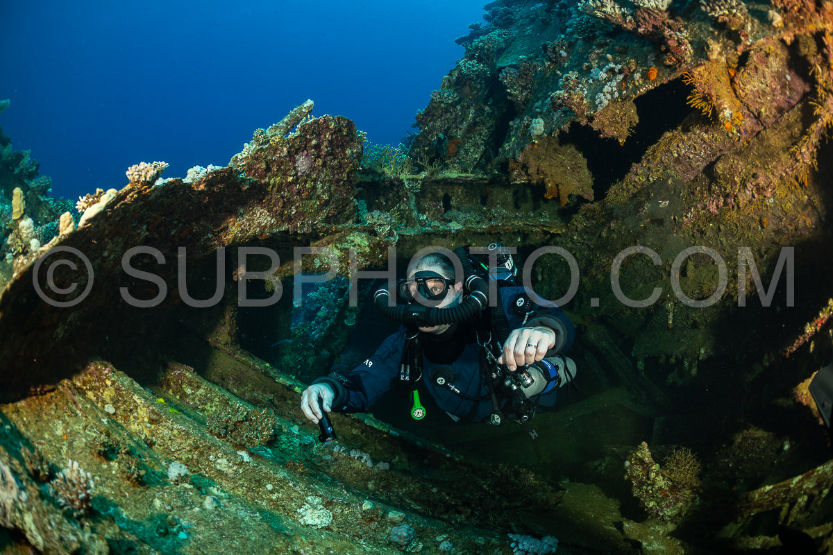 A scuba diver is exploring a shipwreck in the Red Sea. They are using a rebreather to conserve air- which allows them to stay submerged for longer periods.