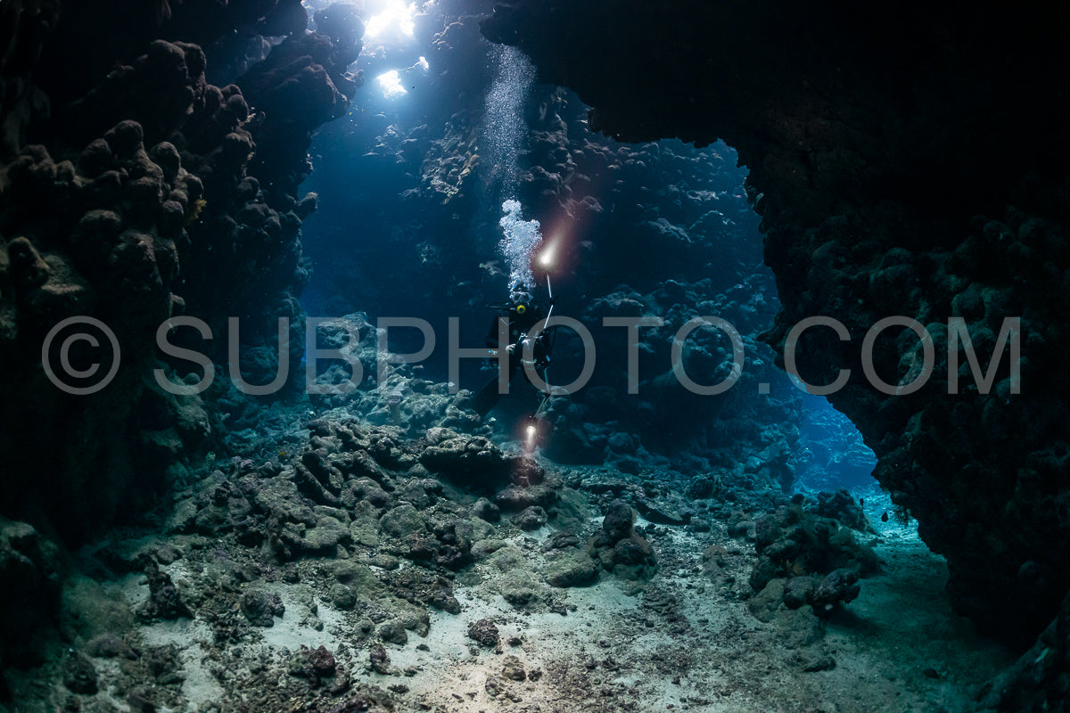 Photo de grotte sous-marine typique dans un récif de mer rouge avec un plongeur photographe sous-marin